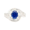 Natural 1.14 Carat Oval Cut Blue Sapphire with Round & Baguette Cut Diamonds in a Swirled 18K White Gold Ring Setting